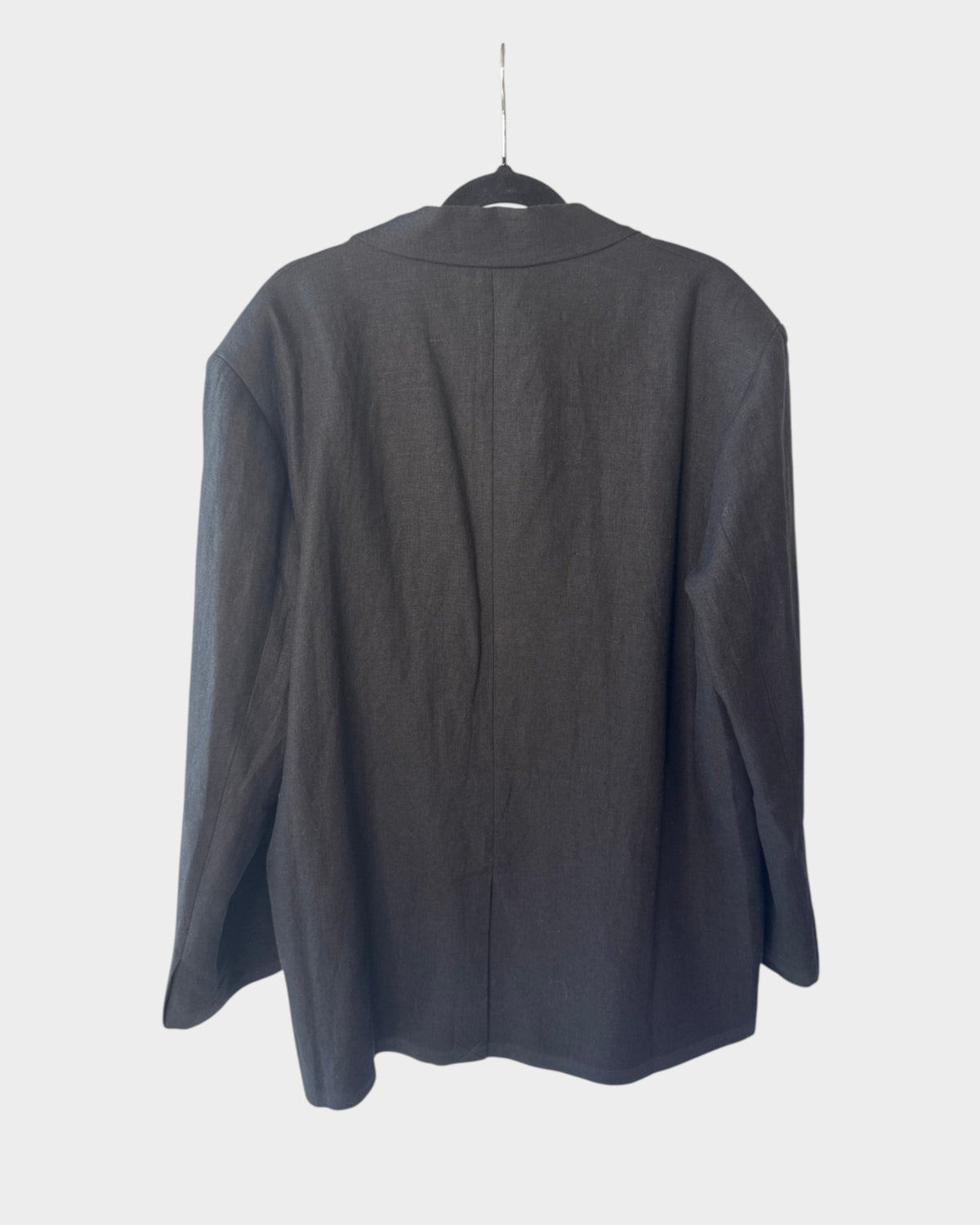 Lula and Mimi AERE oversized black linen blazer hanging on a rack, showing the back view.