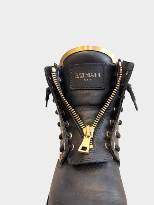 Lula and Mimi Balmain black leather army boots featuring gold hardware, front zipper, and metallic tongue detail.