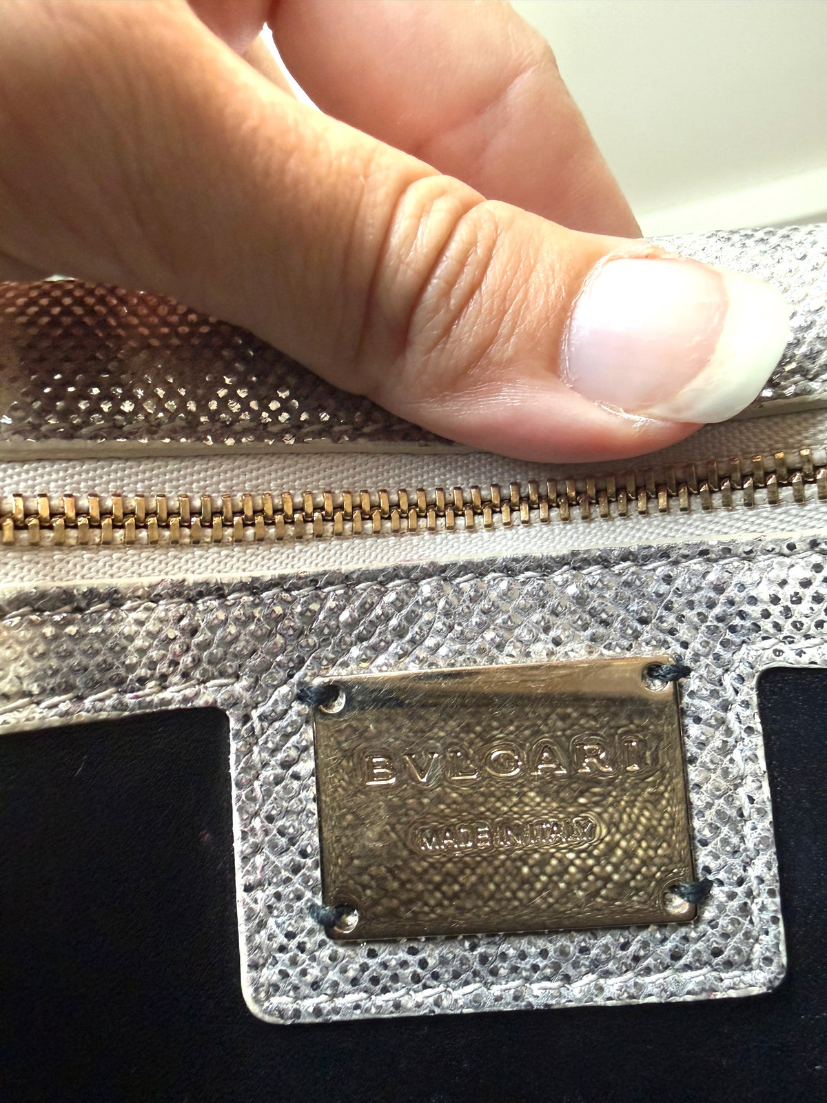 Lula and Mimi Bvlgari Serpenti Cabochon bag interior showing the gold-tone logo plaque on metallic karung skin