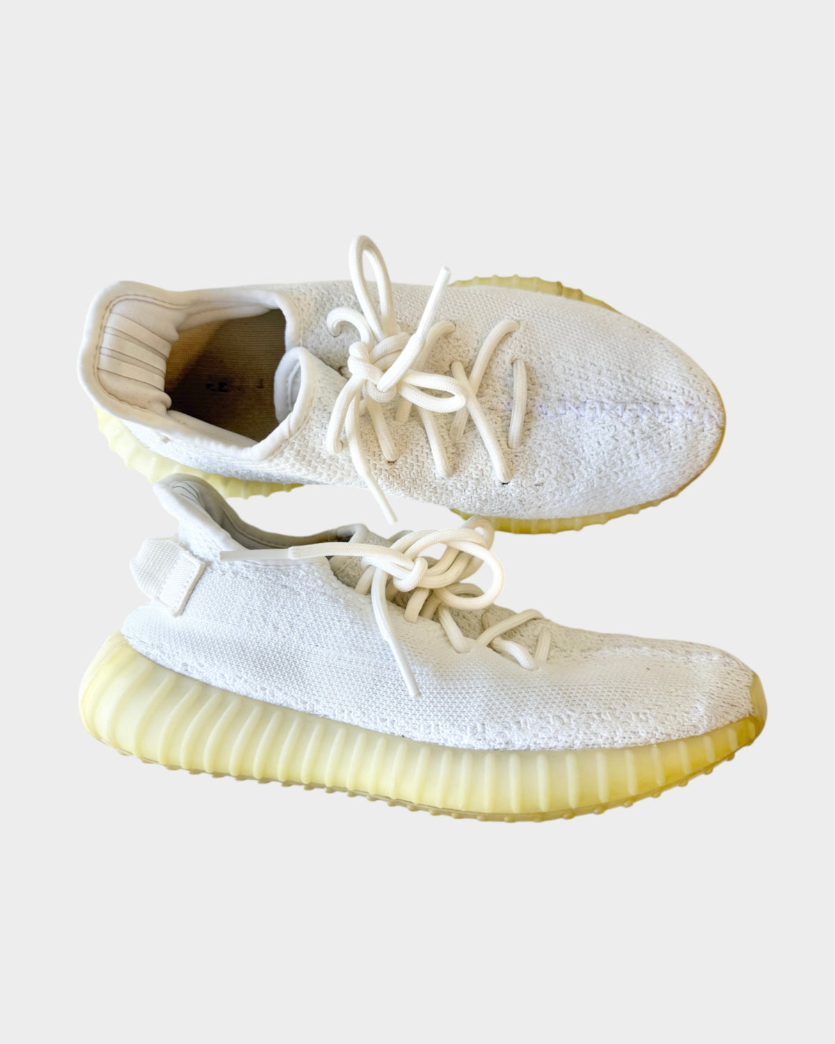 Lula and Mimi Adidas x Yeezy Boost 350 V2 trainers in cream white with a knit upper and ribbed rubber sole.